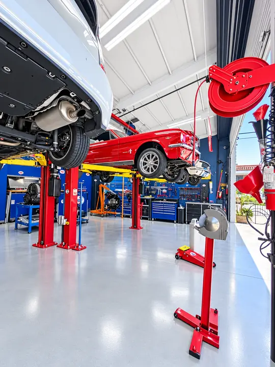 Red two-post lifts and a classic Mustang inside Cedillo's auto repair shop in Fullerton, CA